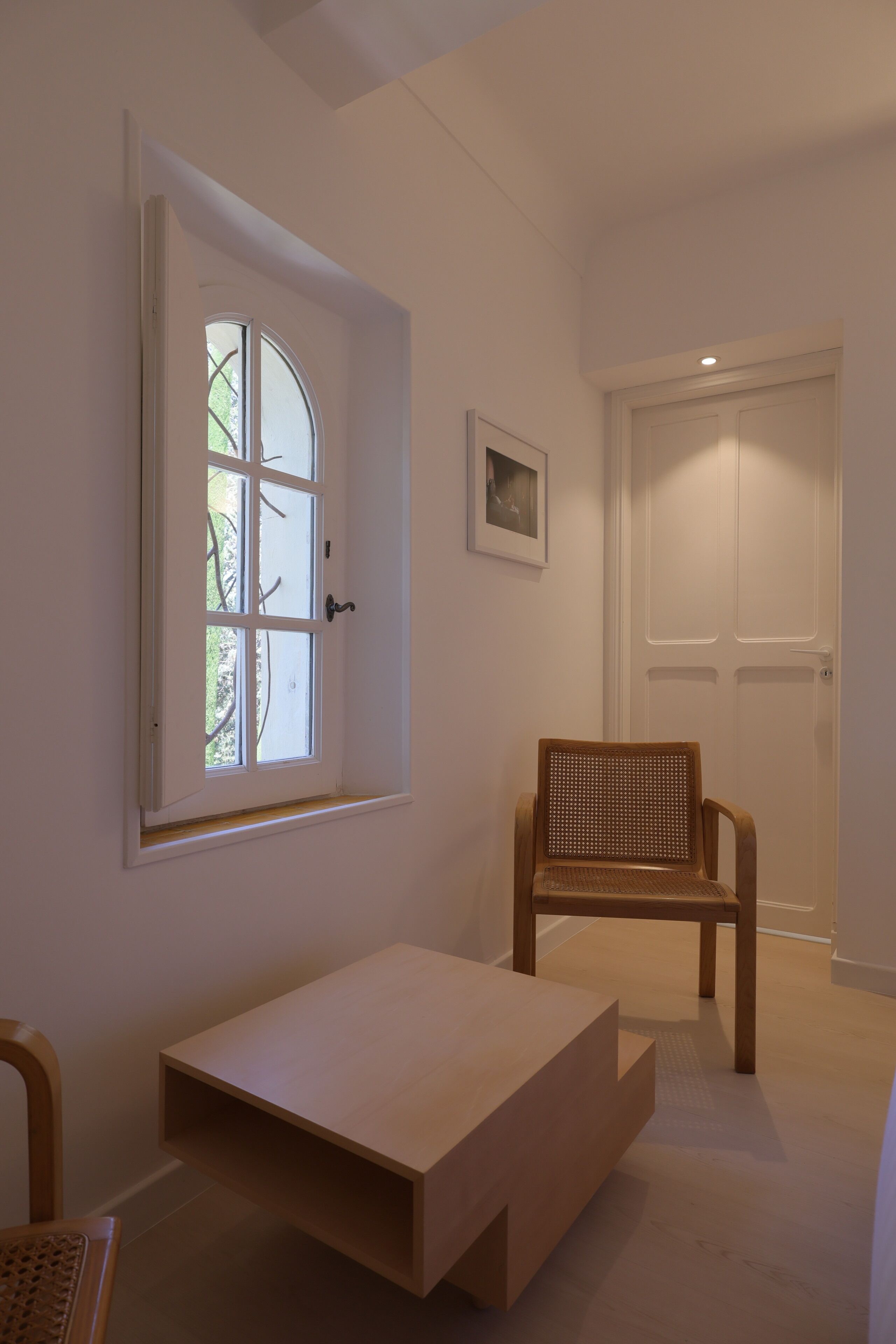 A room with a window, a door, a chair, and a small table.