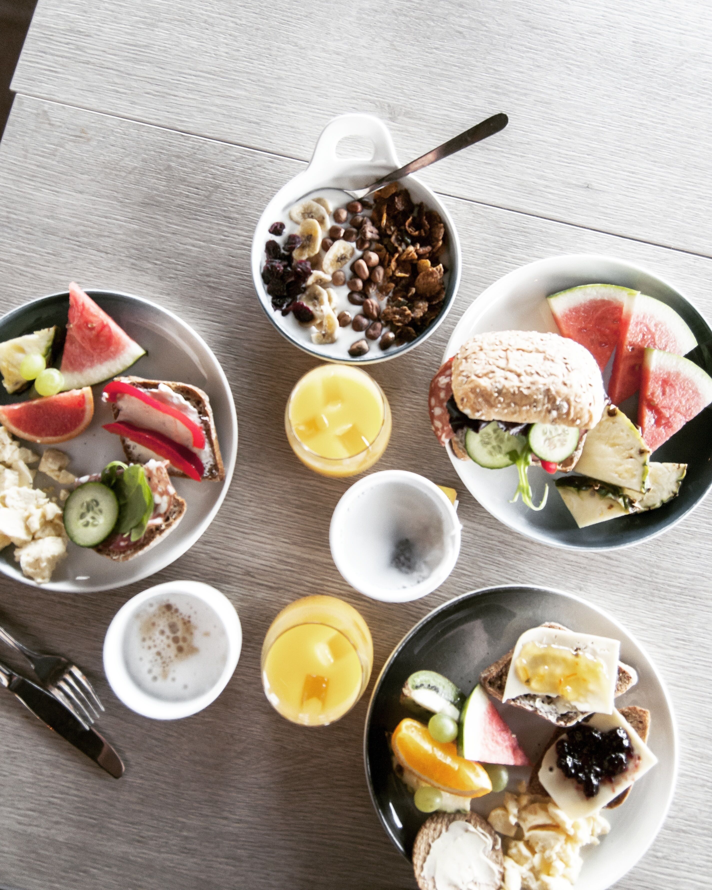 A breakfast spread with various food items and drinks on a wooden table.