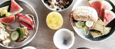 A breakfast spread with various food items and drinks on a wooden table.
