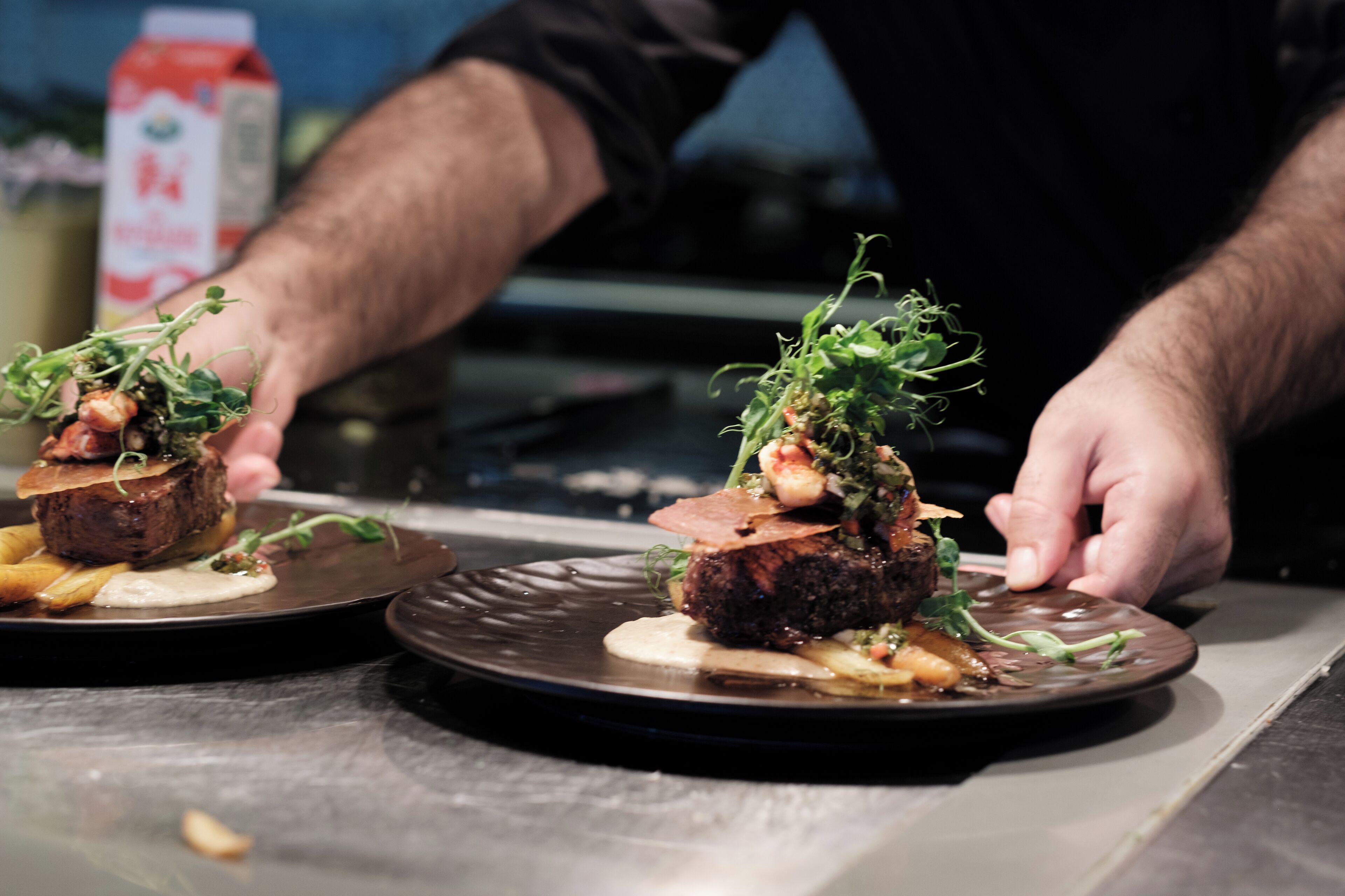 A chef placing a dish on a plate.