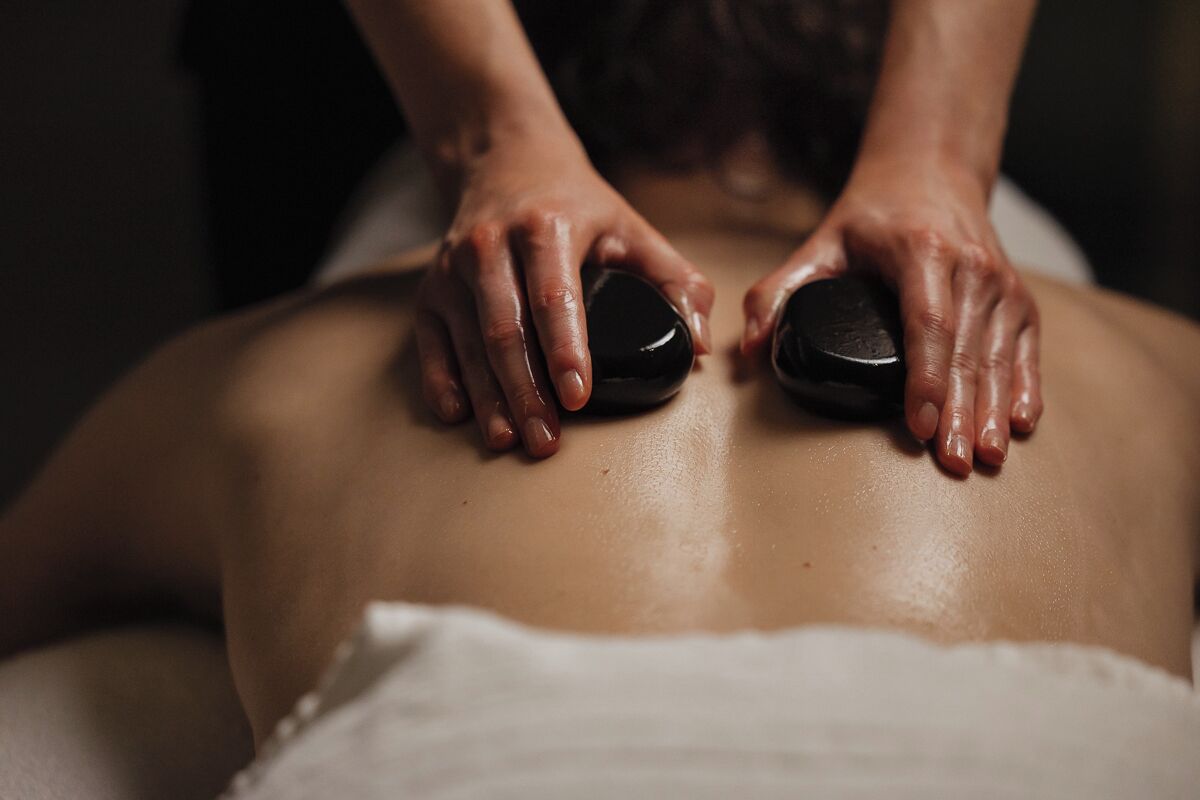 En person modtager massage på ryggen med en varm sten.