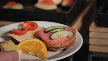 Un plato con un sándwich, rebanadas de sandía y una rodaja de naranja.