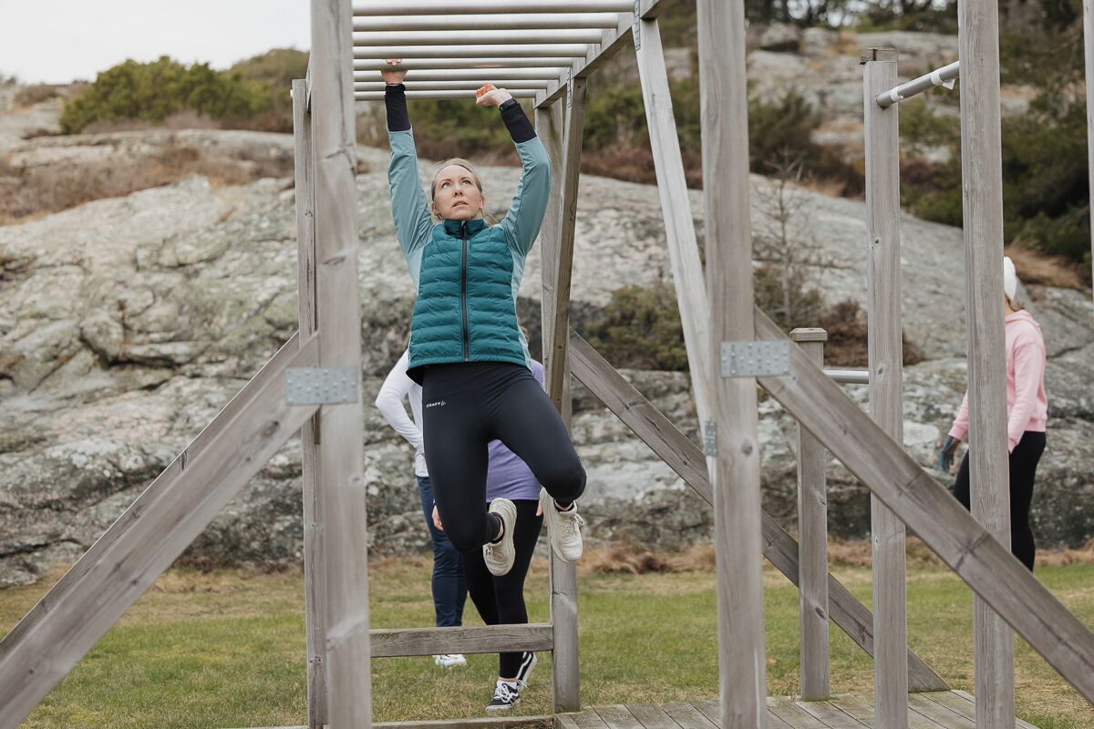 A person performing pull-ups on a wooden structure outdoors.
