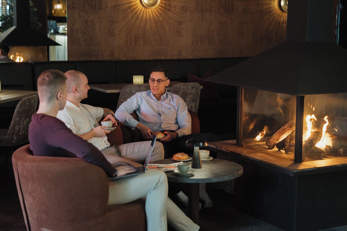 Un espace intérieur accueillant avec une cheminée, des sièges confortables et une table sur laquelle se trouvent un ordinateur portable et une tasse.