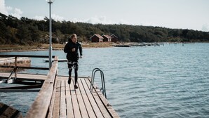 A wooden pier extending into calm water with a person standing at the end.
