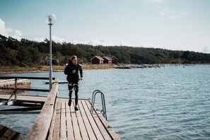 A wooden pier extending into calm water with a person standing at the end.