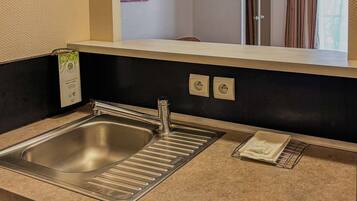 Una cocina moderna con un lavamanos de acero inoxidable, horno empotrado y un pequeño escurreplatos.