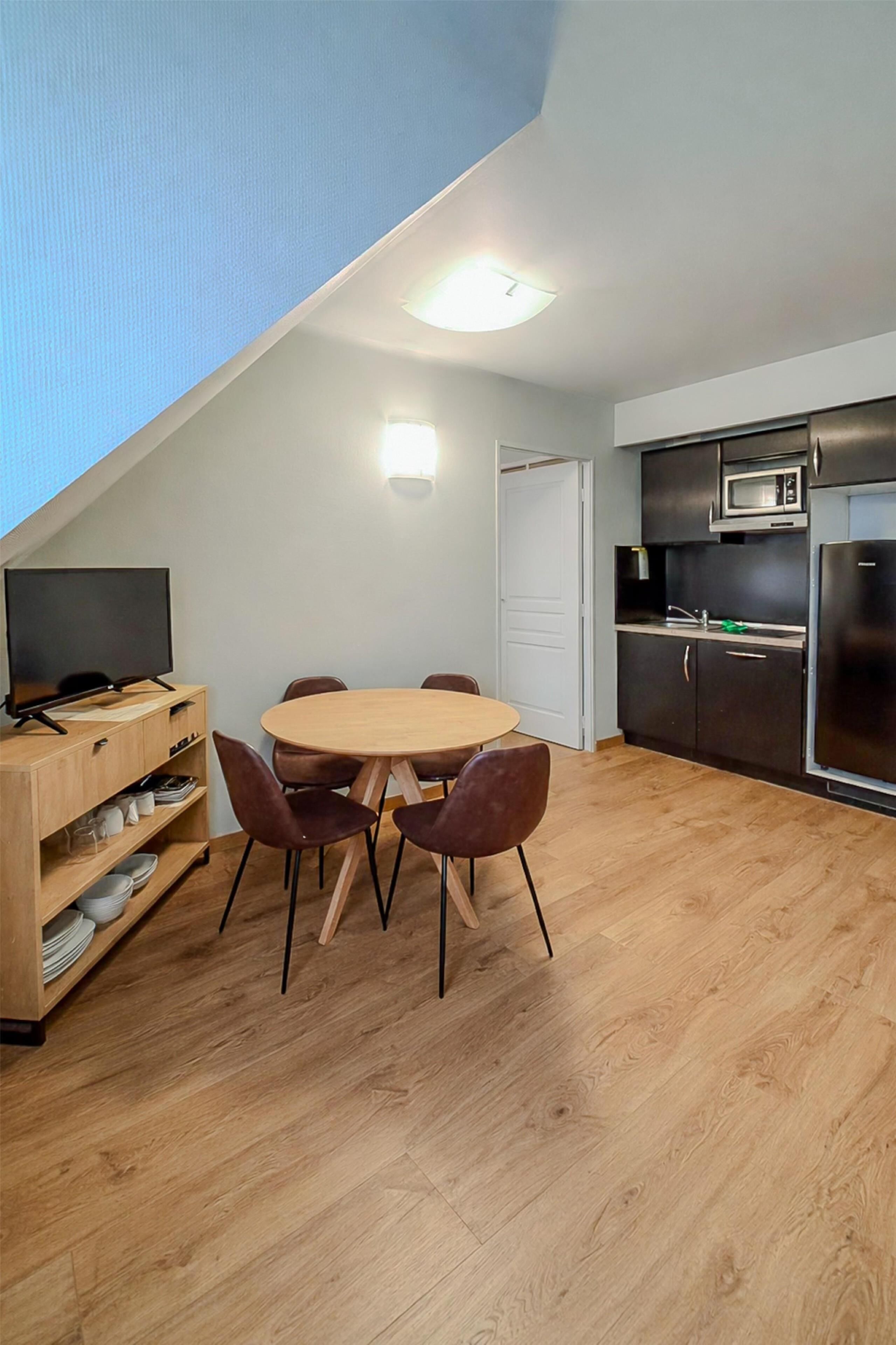 A compact kitchen with a microwave, refrigerator, and wooden cabinets.