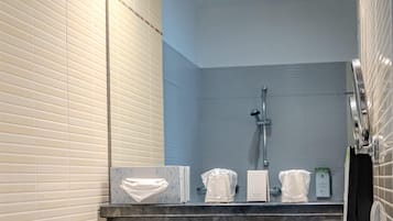 Un baño moderno con un espejo grande, un lavabo con dos toallas y una zona de ducha.