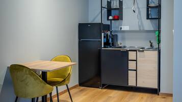 Una cucina compatta con tavolo e sedie, un frigorifero integrato e un piccolo piano di lavoro con lavello.