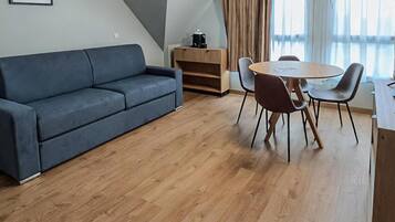 Una sala de estar moderna con un sofá, una mesa de comedor con sillas, una cafetera y una estantería.