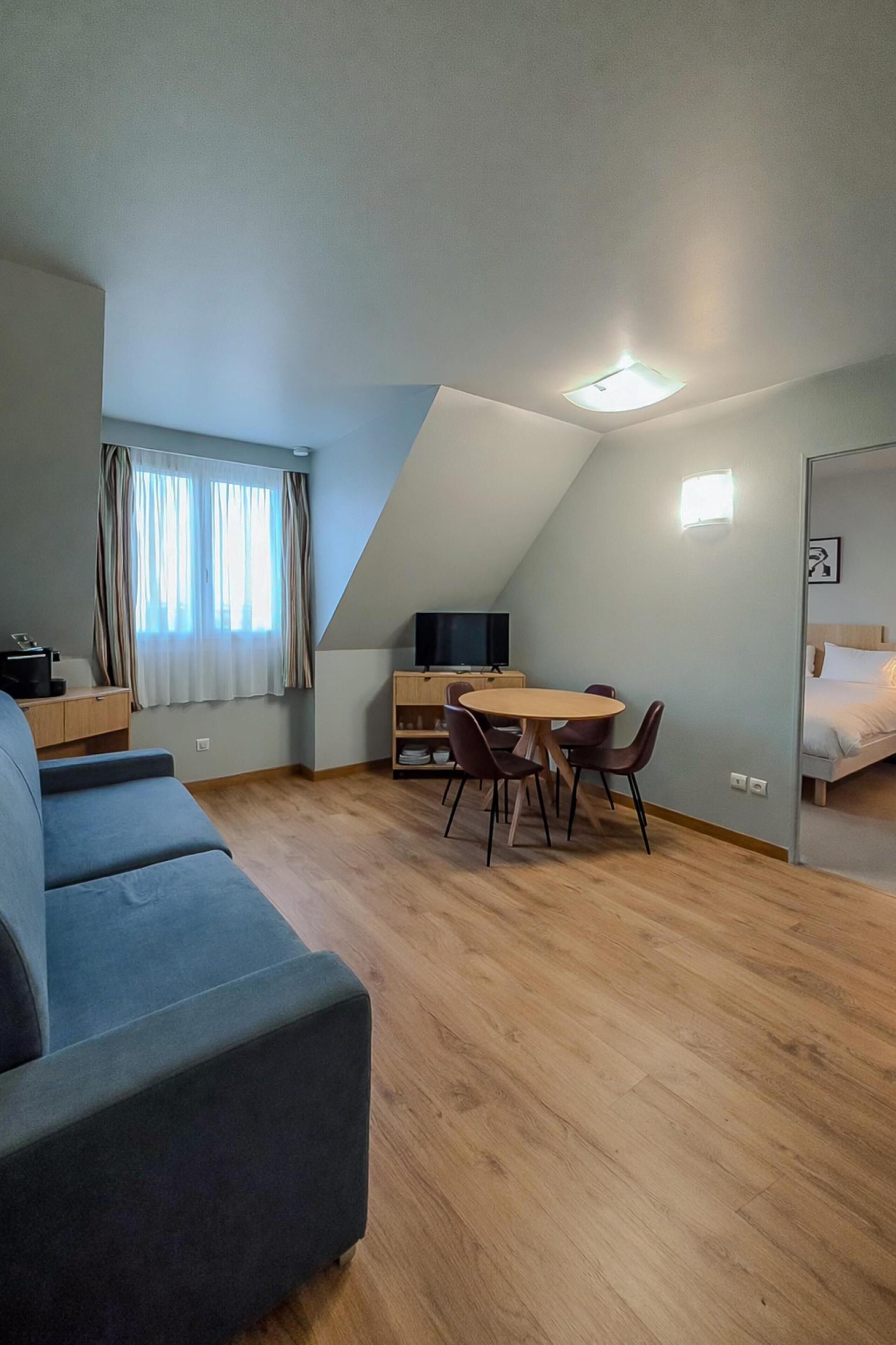 A modern, compact living space with a loft bedroom, a dining area, and a seating area.