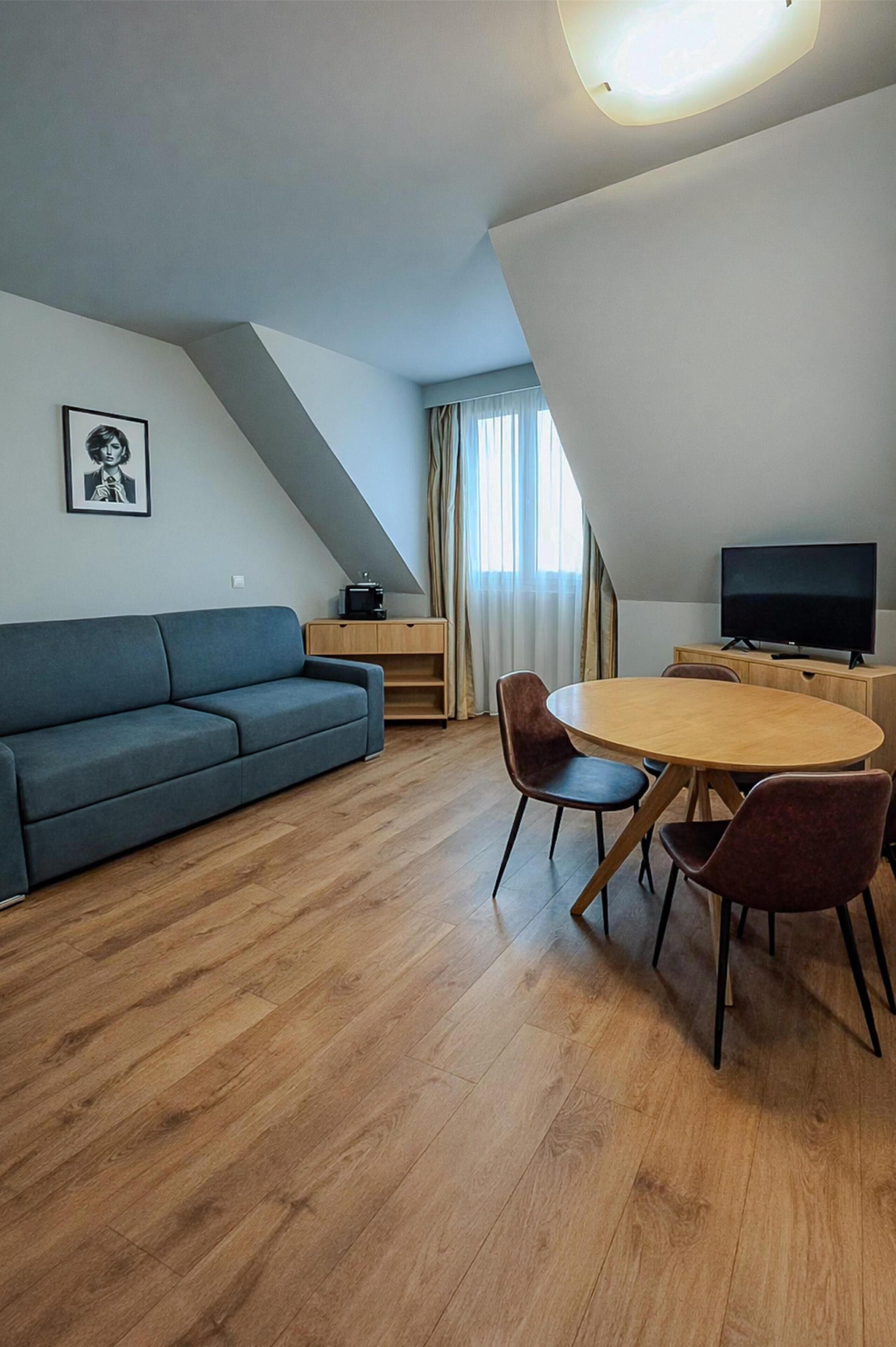 Una sala de estar moderna con un sofá, una mesa de comedor con sillas, un televisor y un mueble de madera.