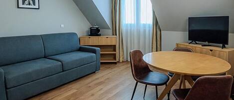 Una sala de estar moderna con un sofá, una mesa de comedor con sillas, un televisor y un mueble de madera.