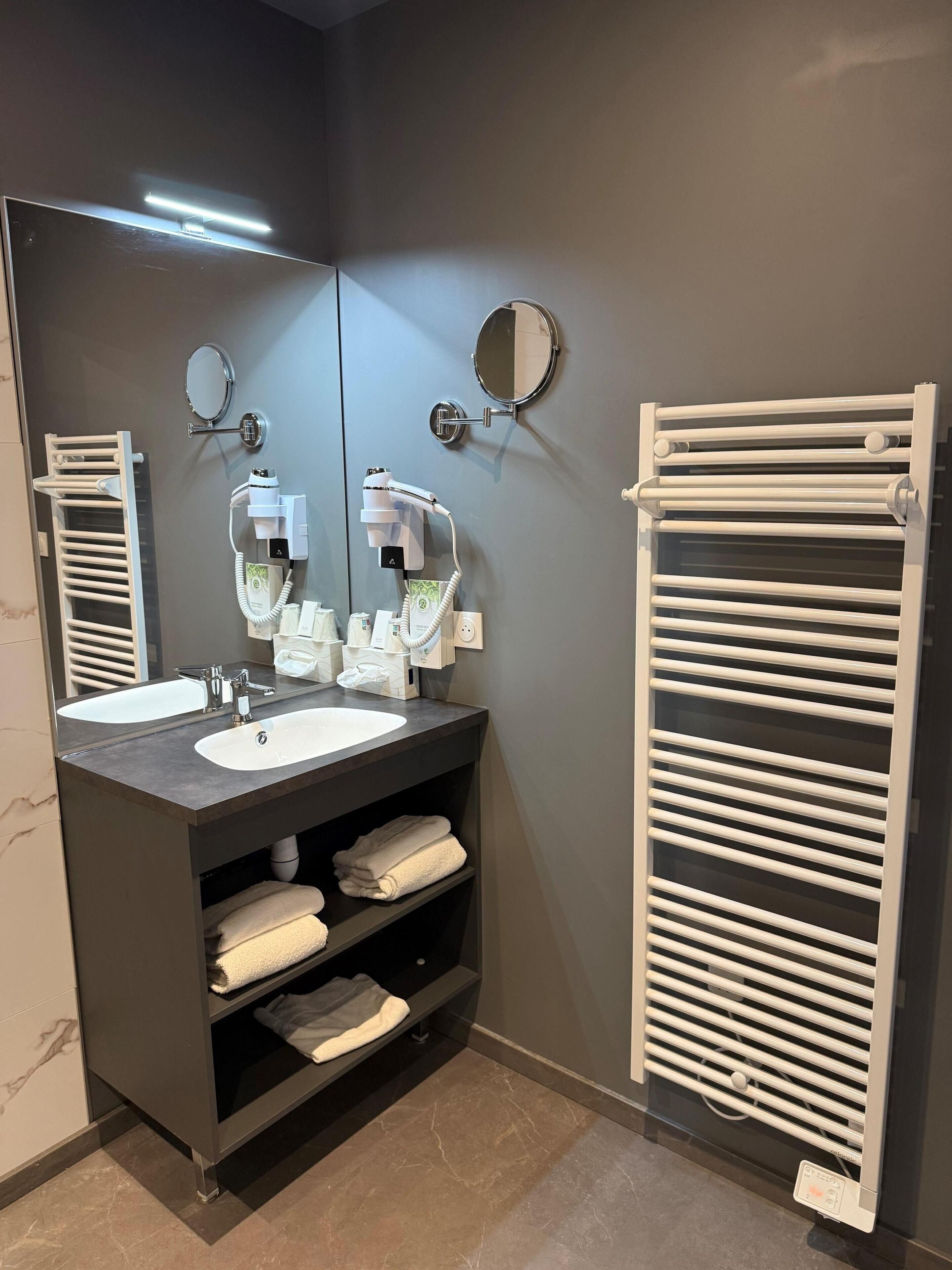 A modern bathroom with a dark marble sink, a mirror, a towel rack, and a hairdryer.