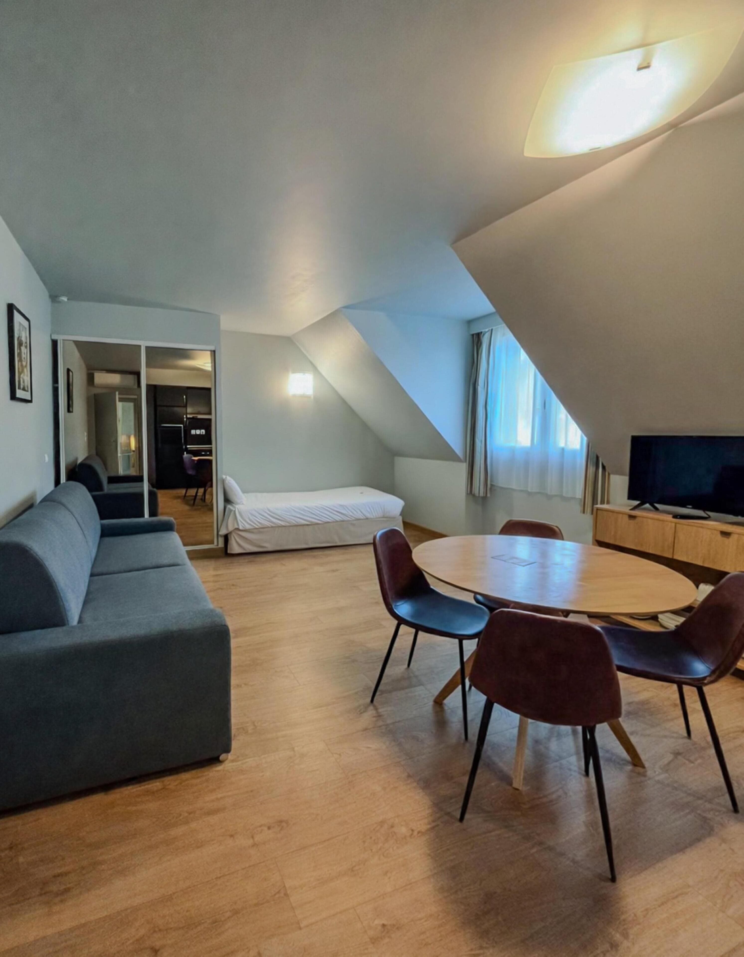 Een modern loft appartement met een eethoek, een bank en een televisie.