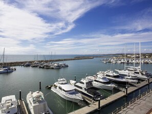 Un puerto deportivo con varias embarcaciones amarradas, un muelle de madera y un cielo despejado.