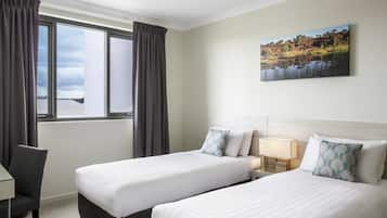 Ein Hotelzimmer mit zwei Betten, einem Schreibtisch und einem Fenster mit Vorhängen.