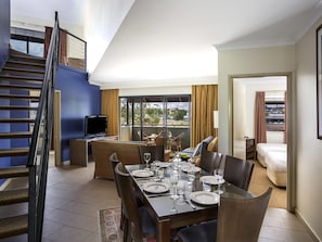 A dining area with a table set for four, a television, and a balcony with outdoor seating.