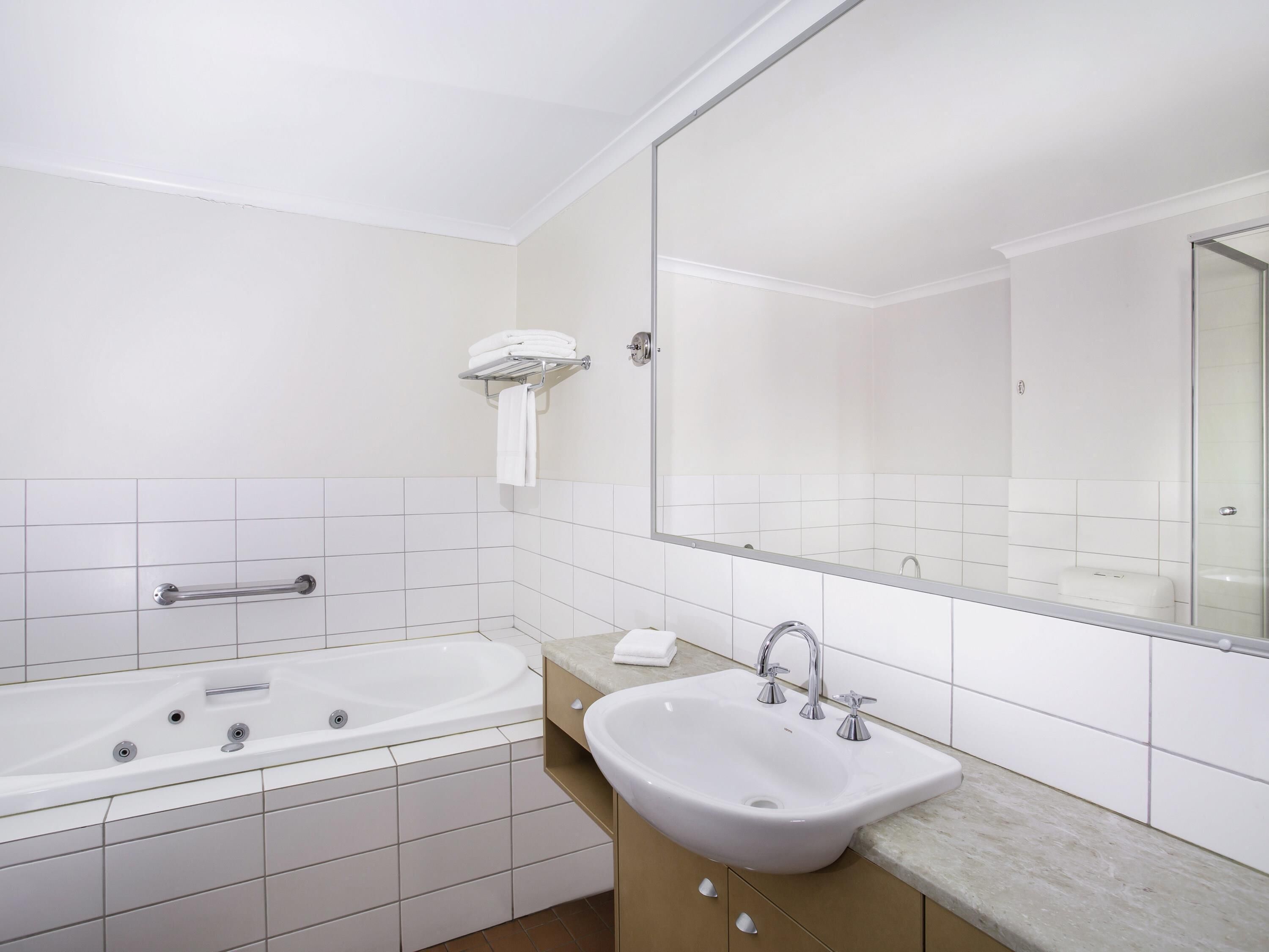 Une salle de bain moderne avec une baignoire, un lavabo et un grand miroir.