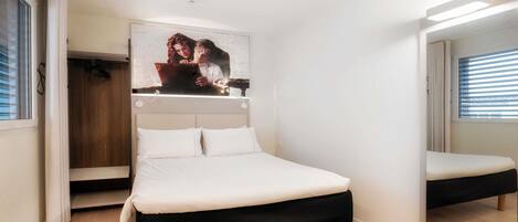 Un dormitorio con cama, armario, espejo y un cuadro colgado en la pared.