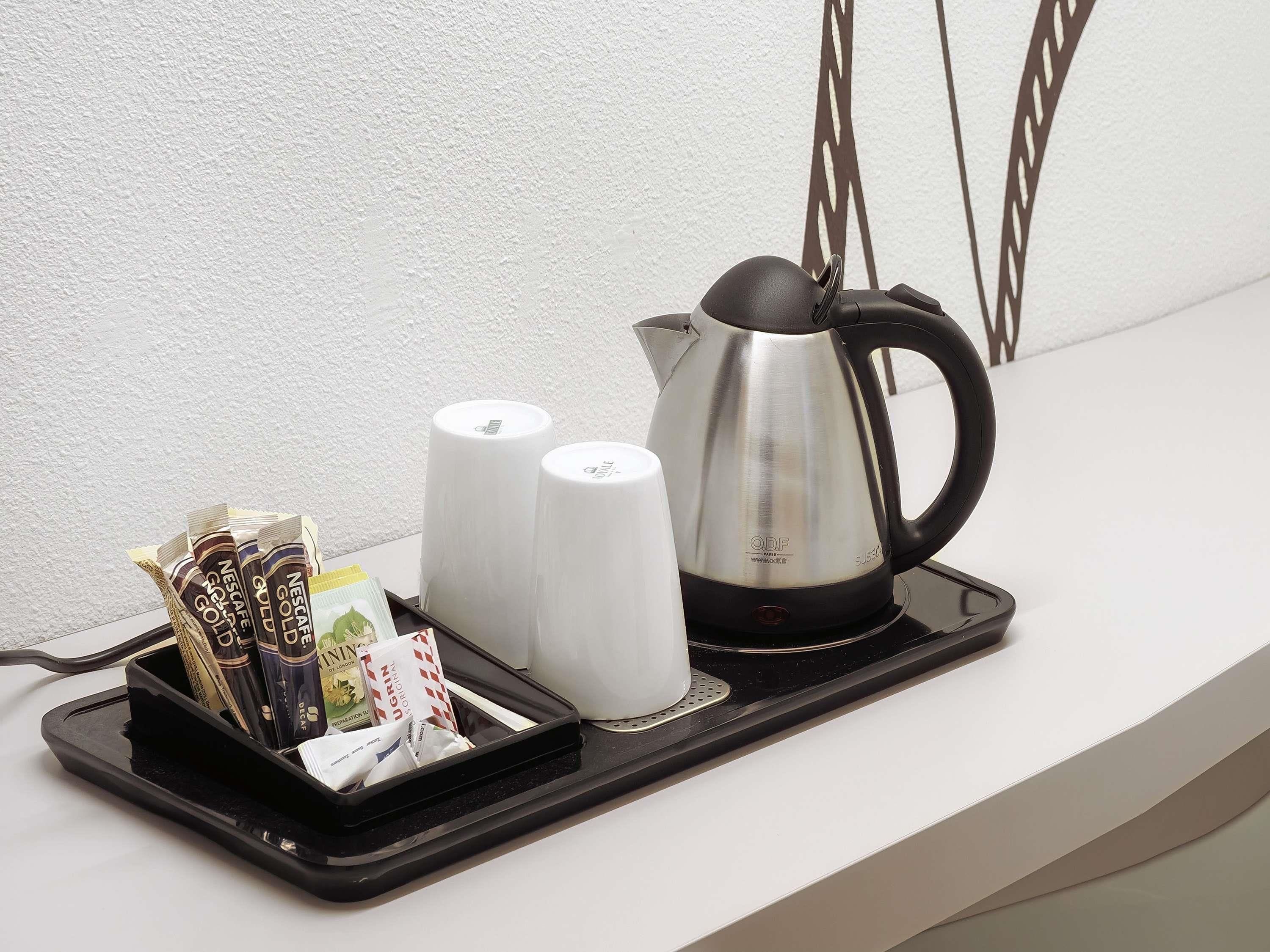 A tray with a coffee maker, salt and pepper shakers, and a container of coffee pods on a white countertop.