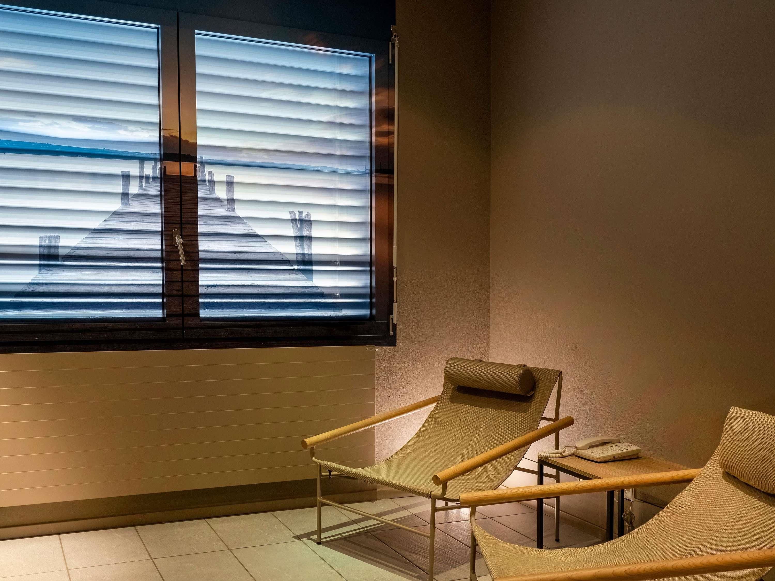 A modern room with a large window, a wooden chair, and a small table with a telephone.