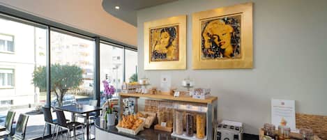 A modern reception area with a counter displaying pastries and condiments, a toaster, and framed artwork on the wall.