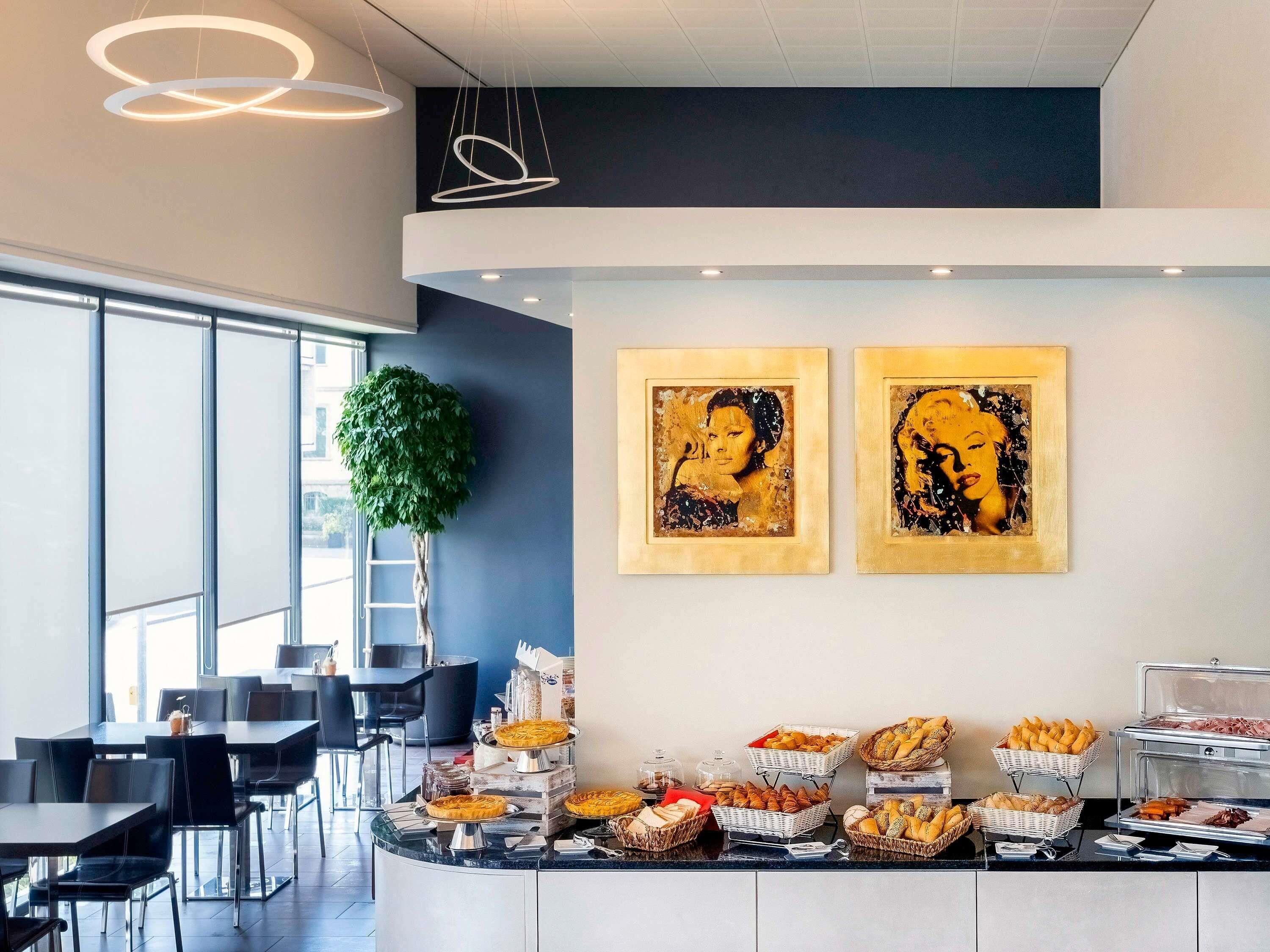 A modern dining area with a buffet, artwork on the wall, and a large window providing natural light.