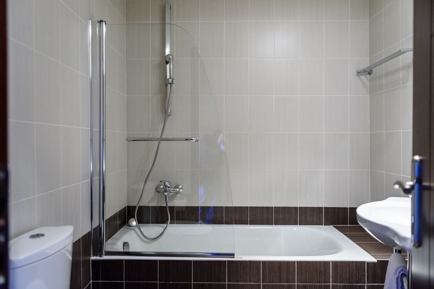 A modern bathroom with a glass-enclosed shower, a white bathtub, and a white sink.