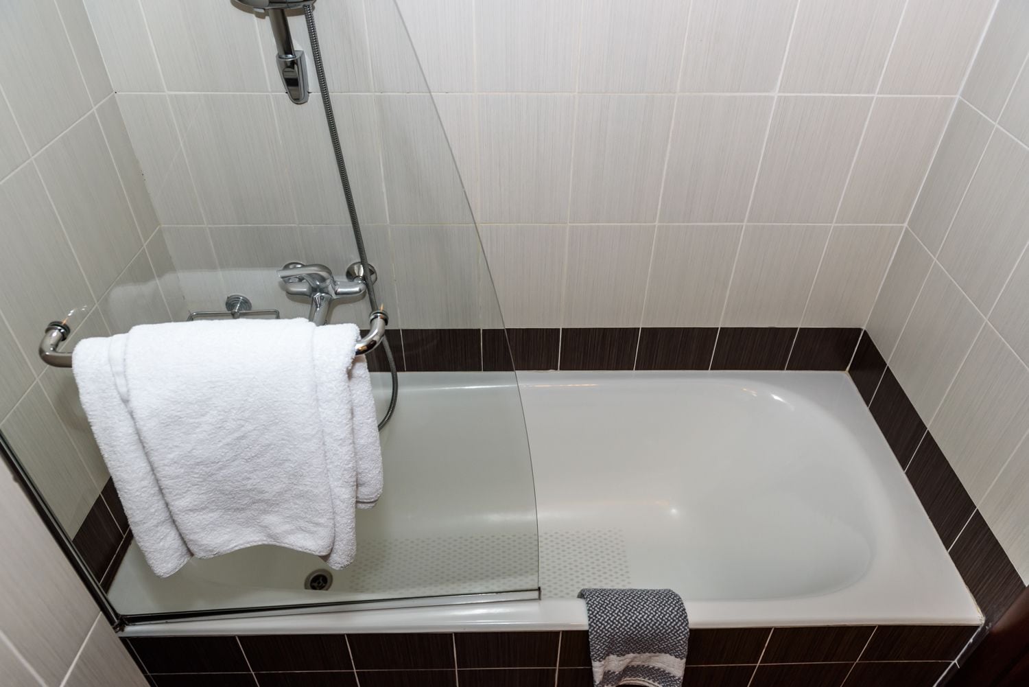 Un bagno con vasca, doccia e porta asciugamani.
