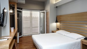 Ein modernes Hotelzimmer mit einem hölzernen Bett, einem Schreibtisch und einem Schrank mit Schiebetüren.