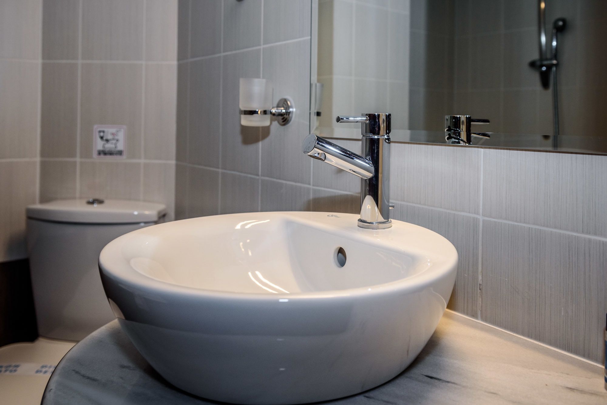 Une salle de bain avec un lavabo blanc, un robinet chromé et un miroir au-dessus.