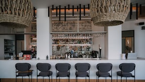 Eine Bar mit einer Theke, mehreren Stühlen und Flaschenregalen.