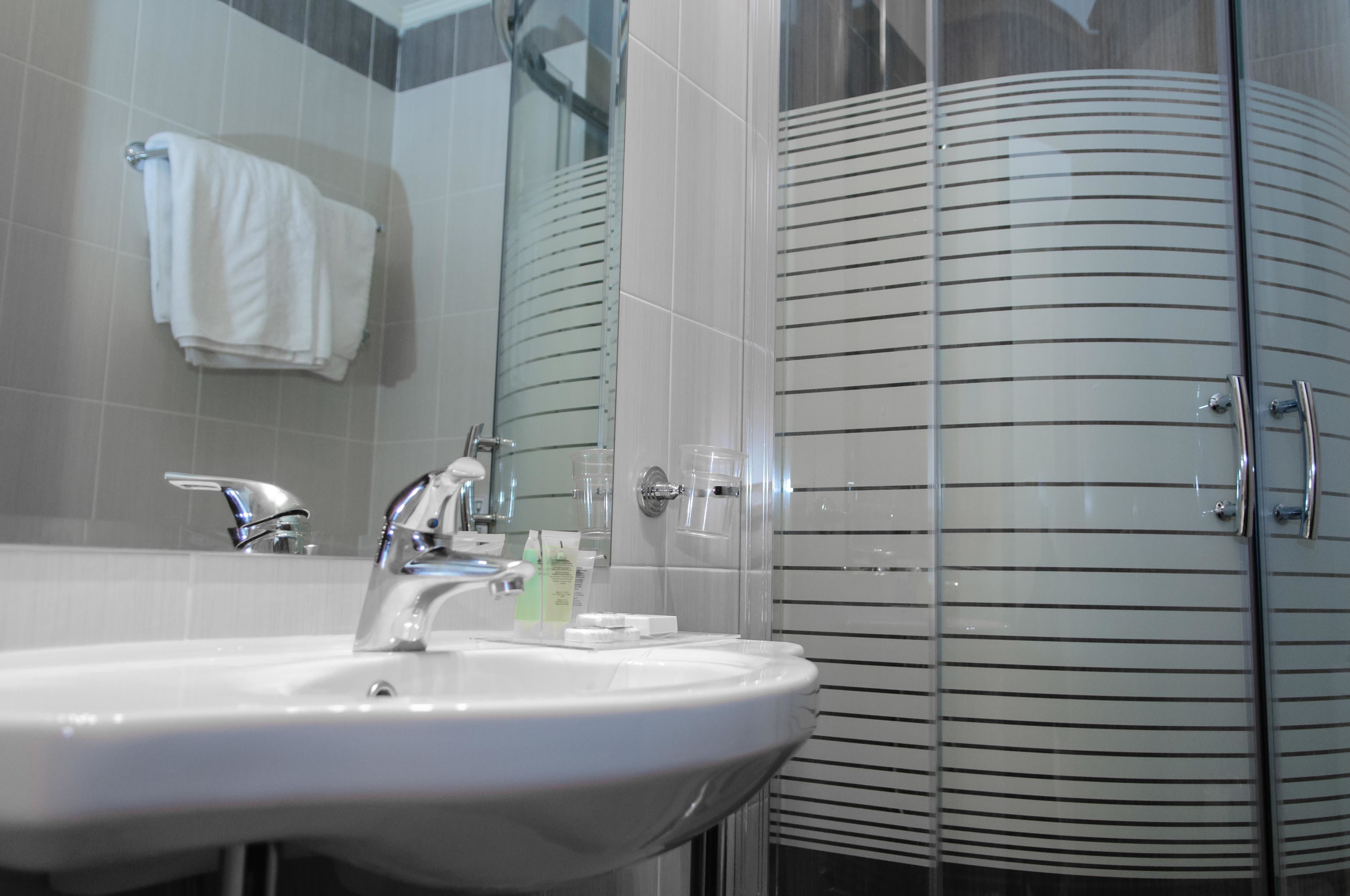 A bathroom with a sink, mirror, and glass shower enclosure.