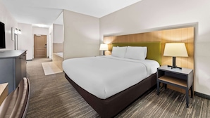 Een hotelkamer met een groot bed, nachtkastjes met lampen, een bureau en een televisie.
