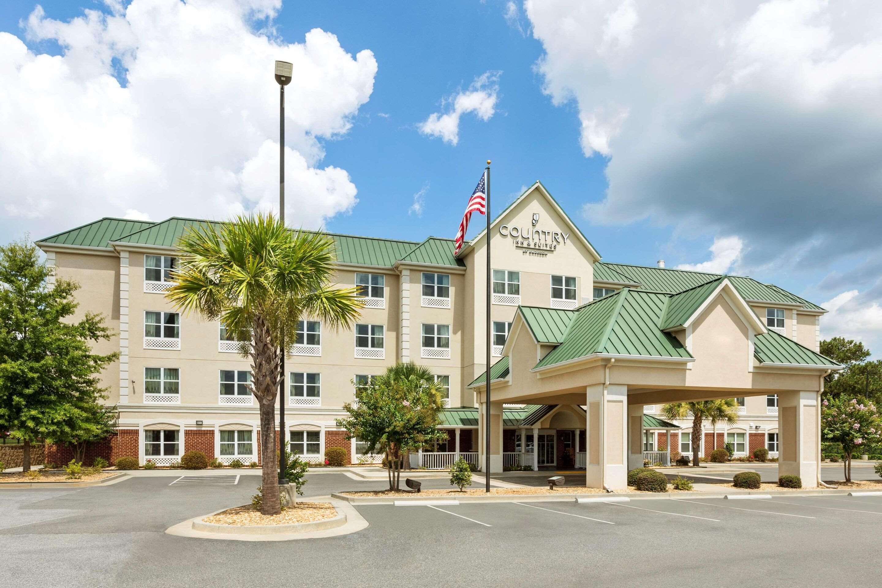 A hotel with a green roof, a flag, and a covered entrance.