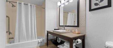 Un baño con una bañera, un lavabo con espejo y un inodoro.