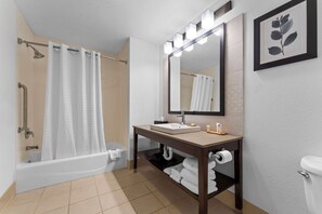 A bathroom with a bathtub, a sink with a mirror, and a toilet.