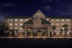 A Country Inn & Suites building with a large entrance, multiple windows, and a parking lot.