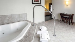 Een moderne badkamer met een vrijstaand bad, een douchegedeelte en een klein tafeltje met stoelen.