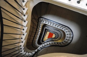 Una scala a chiocciola con ringhiere in metallo e un pannello decorativo centrale rosso e giallo.