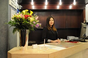 Mostrador de recepción con un florero, una computadora y un teléfono.