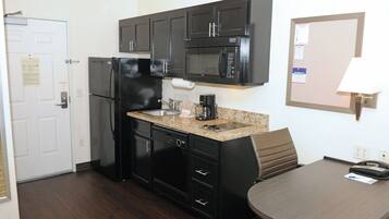 A compact kitchen with a refrigerator, microwave, sink, and a small dining area with a table and chairs.