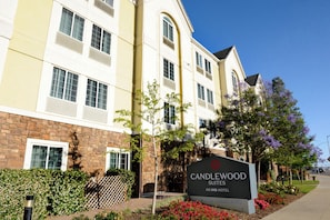 Un letrero de hotel con el texto 'CANDLEWOOD SUITES' y 'UN HOTELO IHG', indicando que la propiedad forma parte de la cadena IHG.
