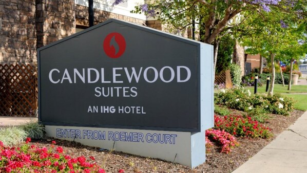 Señalización de Candlewood Suites, un hotel IHG, con logotipo rojo e indicaciones de acceso desde Roemer Court.