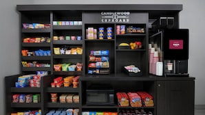Une petite cuisine équipée d’étagères remplies de collations, de boissons et d’une machine à café.
