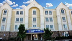 Un hôtel à plusieurs étages, doté d’une façade symétrique, de grandes fenêtres et d’une entrée imposante surmontée d’un auvent bleu portant l’inscription « CANDLEWOOD SUITES ».