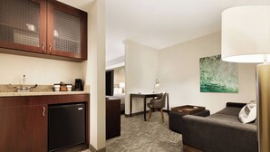 Ein kompaktes Hotelzimmer mit Küchenzeile, einem Essbereich und einer Sitzecke mit Sofa und Lampe.