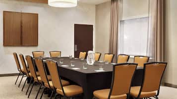 Une salle de conférence équipée d’une grande table, de chaises et d’une carafe d’eau.